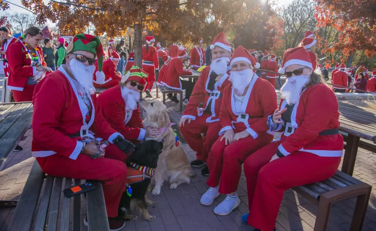 Group of people dressed as Santa with a dog