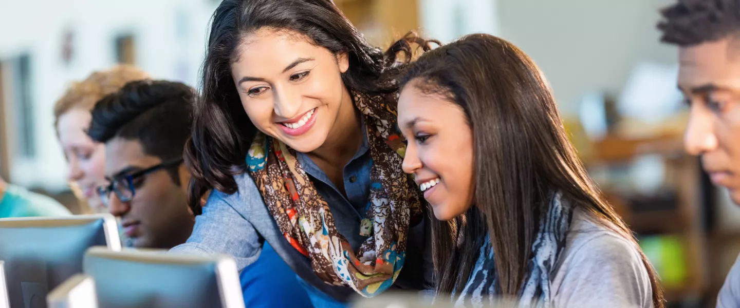 woman helping woman on the computer smiling